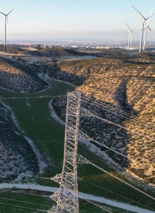 Une ligne à haute tension à côté d'un champ d'éoliennes