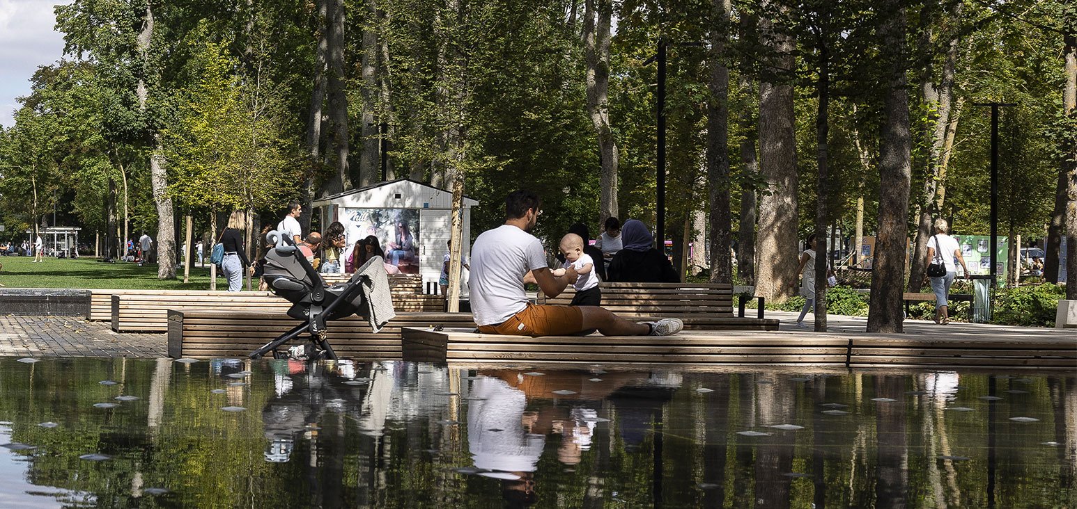 Un père et son fils près d'un plan d'eau, dans un parc de centre-ville