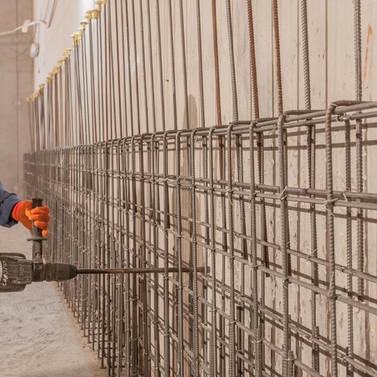 Un ouvrier travaillant au marteau piqueur sur le mur d'un chantier