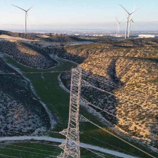 Une ligne à haute tension à côté d'un champ d'éoliennes