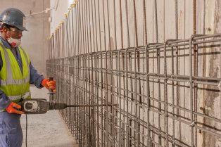 Un ouvrier travaillant au marteau piqueur sur le mur d'un chantier