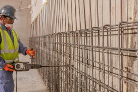 Un ouvrier travaillant au marteau piqueur sur le mur d'un chantier